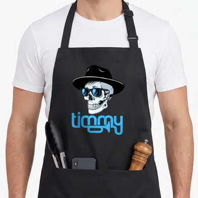 Tablier de cuisine noir avec un crâne coiffé d'un chapeau et des lunettes de soleil bleues surmontant le texte timmy.
