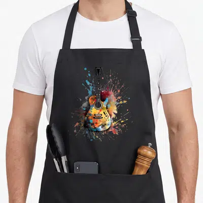 Tablier de cuisine noir avec une illustration de guitare électrique multicolore entourée d'éclaboussures de peinture.