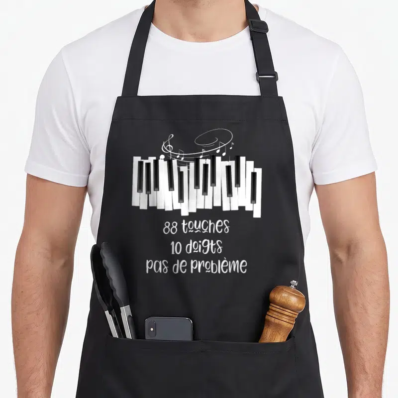 Tablier de cuisine noir avec illustration de clavier de piano et texte 88 touches 10 doigts pas de problème en blanc.