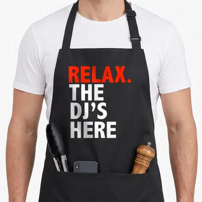 Tablier de cuisine noir portant l'inscription Relax. The DJ's Here en lettres rouges et blanches.