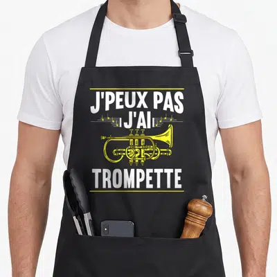 Tablier de cuisine noir avec inscription blanche Je peux pas j'ai trompette et illustration de cuivre jaune sur fond uni.