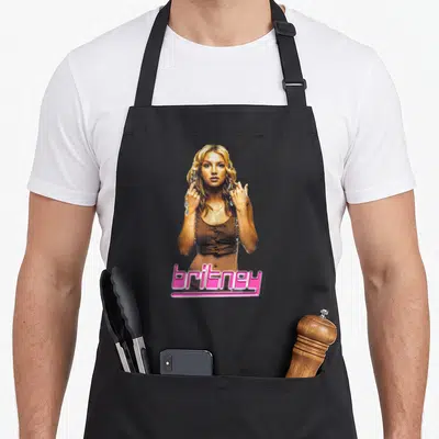 Tablier de cuisine noir avec une illustration de Britney Spears et son nom écrit en rose vif en bas de page.