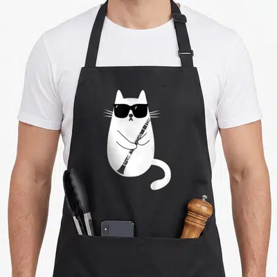 Tablier de cuisine noir avec illustration d'un chat blanc jouant de la clarinette sous des lunettes noires.