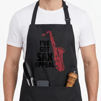 Tablier de cuisine noir avec illustration saxophone rouge et texte I've Got Sax Appeal en typographie noire usée.