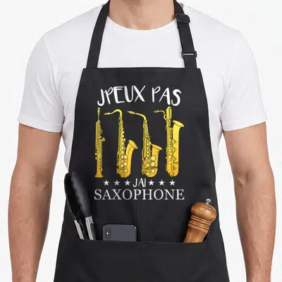 Tablier de cuisine noir avec inscription Jpeux pas j'ai saxophone et quatre saxophones jaunes alignés verticalement.