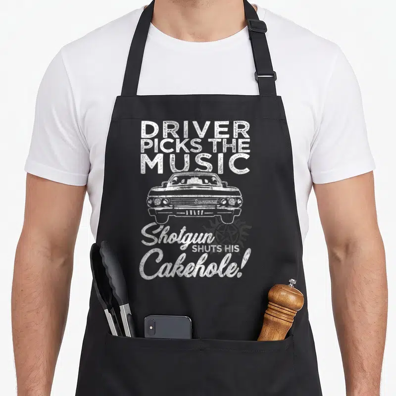 Tablier de cuisine noir avec illustration voiture blanche et texte Driver Picks The Music Shotgun Shuts His Cakehole.