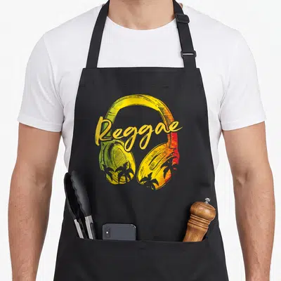 Tablier de cuisine noir avec casque Reggae Music aux couleurs vert, jaune et rouge et silhouettes de palmiers.
