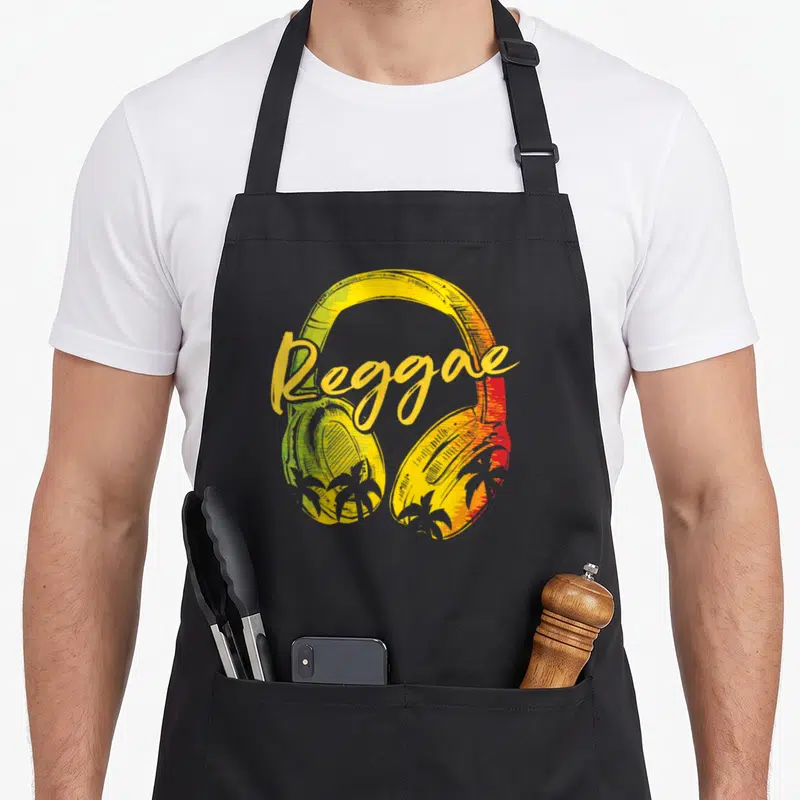 Tablier de cuisine noir avec casque Reggae Music aux couleurs vert, jaune et rouge et silhouettes de palmiers.