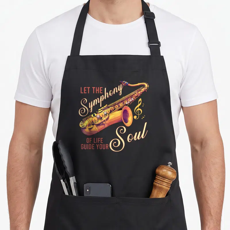 Tablier de cuisine noir avec illustration colorée d'un saxophone et typographie artistique en anglais.