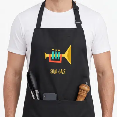 Tablier de cuisine noir avec illustration de trompette jaune et texte Soul Jazz en bas du motif central.