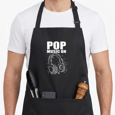 Tablier de cuisine noir avec illustration blanche de casque audio et texte Pop Music On entouré d'étoiles.