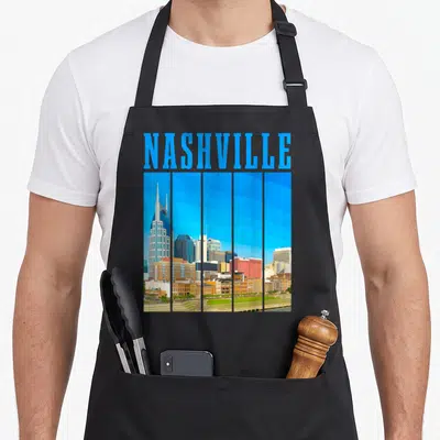 Tablier de cuisine noir avec illustration du skyline de Nashville et texte bleu en haut.