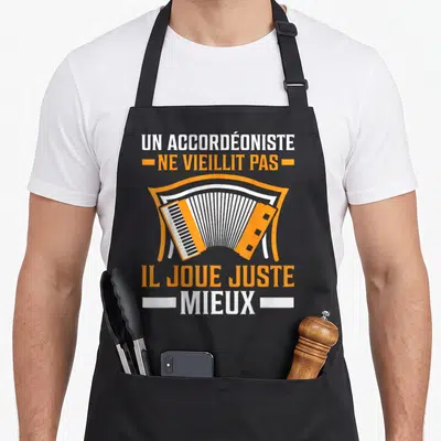 Tablier de cuisine noir avec illustration d'accordéon orange et texte blanc et orange sur fond uni.