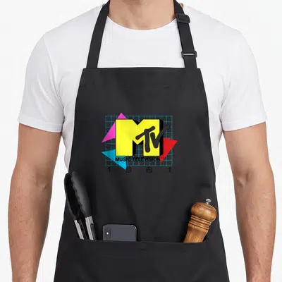 Tablier de cuisine noir avec le logo MTV Music Television 1981 aux couleurs vives et formes géométriques sur fond gris.