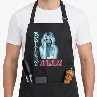 Tablier de cuisine noir avec portrait de Britney Spears et texte vertical BRITNEY horizontal SPEARS en style néon bleu et rose.