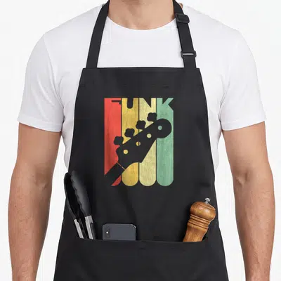 Tablier de cuisine noir avec une tête de basse grise sur fond de bandes vertes, jaunes et rouges formant le mot FUNK.