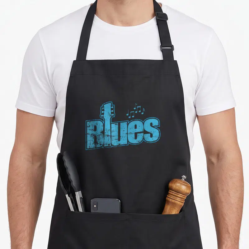 Tablier de cuisine noir avec motif bleu « Blues », tête de guitare et notes musicales stylisées.