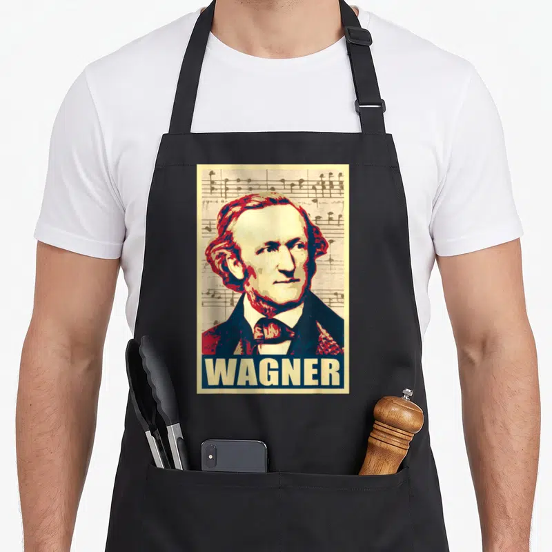 Tablier de cuisine noir avec portrait stylisé de Richard Wagner et le mot WAGNER imprimé en bas sur fond de portées musicales.