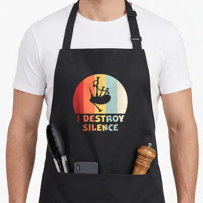 Tablier de cuisine noir avec illustration vintage d'une cornemuse et le texte I DESTROY SILENCE en lettres colorées.