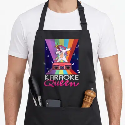 Tablier de cuisine noir avec illustration d'un poney blanc sur une boombox rose et texte Karaoke Queen.