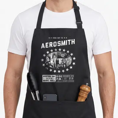 Tablier de cuisine noir avec illustration vintage du groupe Aerosmith et des étoiles blanches.