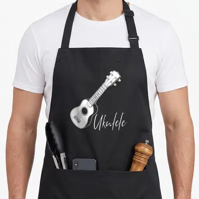 Tablier de cuisine noir avec illustration blanche d'un ukulélé et du mot Ukulele en calligraphie.