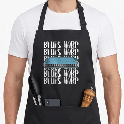 Tablier de cuisine noir avec illustration harmonica bleu et texte BLUES HARP répété en blanc.