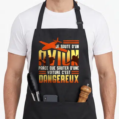 Tablier de cuisine noir avec illustration orange et texte blanc sur le parachutisme humoristique.