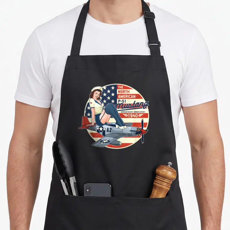 Tablier de cuisine noir avec une pinup posant sur un avion P-51 Mustang aux couleurs du drapeau américain.
