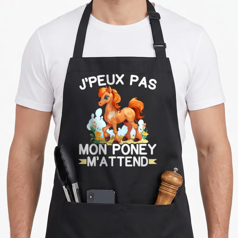 Tablier de cuisine noir avec un poney orange dessiné et le texte Je peux pas mon poney m'attend en blanc.