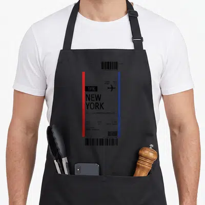 Tablier de cuisine noir avec une carte d'embarquement imprimée vers New York en première classe, bordé de rouge et de bleu.