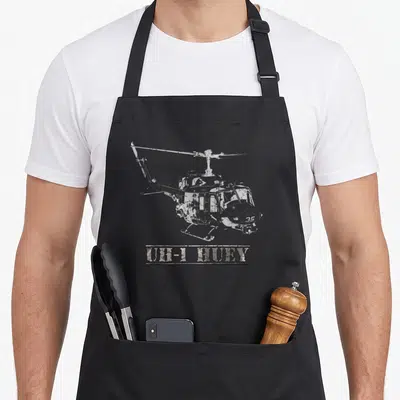 Tablier de cuisine noir avec dessin technique d'un hélicoptère UH-1 Huey et texte en relief sous l'appareil.