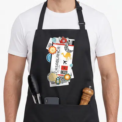 Tablier de cuisine noir avec un motif ticket de voyage Casablanca orné de symboles marocains colorés.