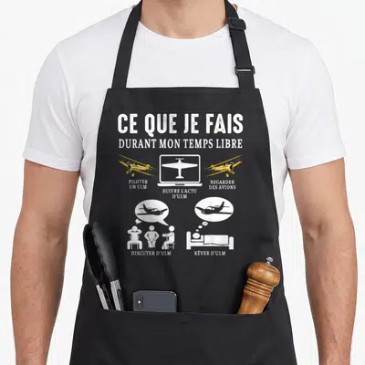 Tablier de cuisine noir avec illustrations blanches et jaunes représentant le pilotage d'ULM et la veille aviation.