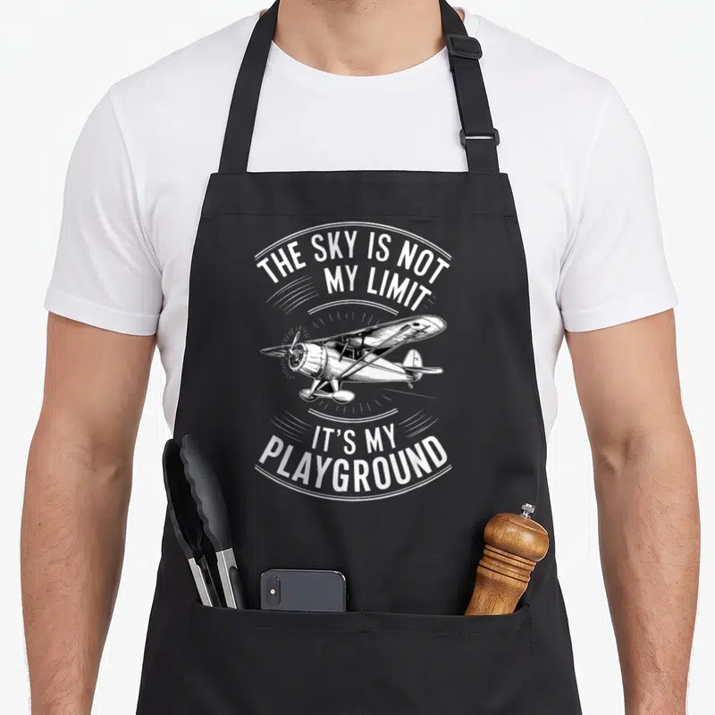 Tablier de cuisine noir avec illustration d'avion biplan et texte blanc The Sky Is Not My Limit It's My Playground.