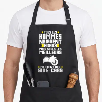 Tablier de cuisine noir avec texte blanc et jaune Tous les hommes naissent égaux mais seuls les meilleurs pilotent des side-cars au-dessus d'une moto silhouette blanche.