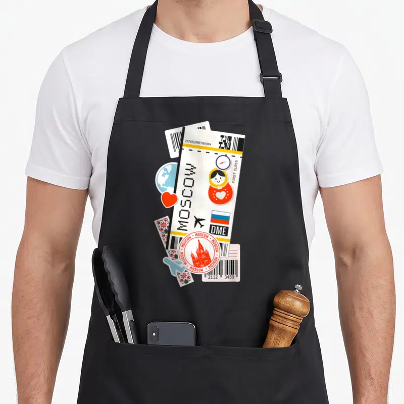 Tablier de cuisine noir avec une illustration de billet d'avion pour Moscou, ours russe et drapeau.