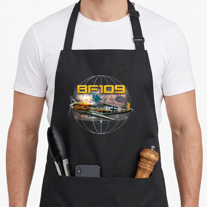 Tablier de cuisine noir avec illustration d'un avion de chasse jaune sur fond de carte géographique circulaire.
