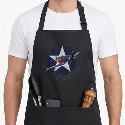 Tablier de cuisine noir avec illustration d'un F4U Corsair sur une étoile bleue et le texte F4U CORSAIR en arc de cercle.