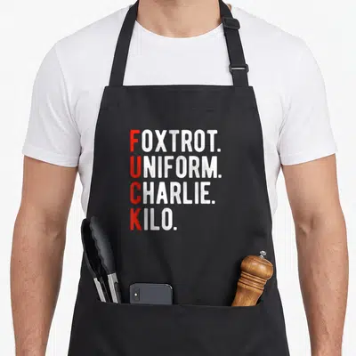 Tablier de cuisine noir avec le texte Foxtrot Uniform Charlie Kilo en lettres rouges et blanches.