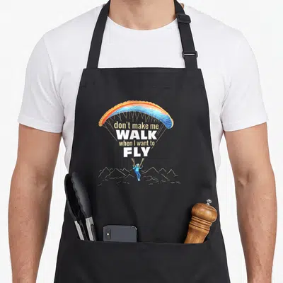 Tablier de cuisine noir avec un parapente multicolore et le texte don't make me walk when I want to fly au centre.