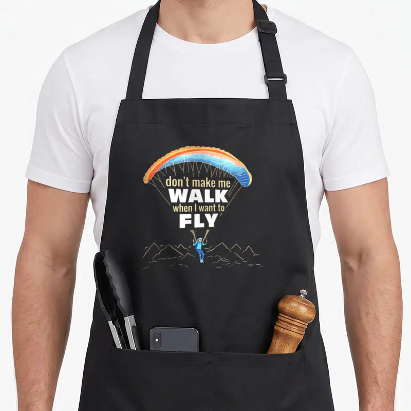 Tablier de cuisine noir avec un parapente multicolore et le texte don't make me walk when I want to fly au centre.