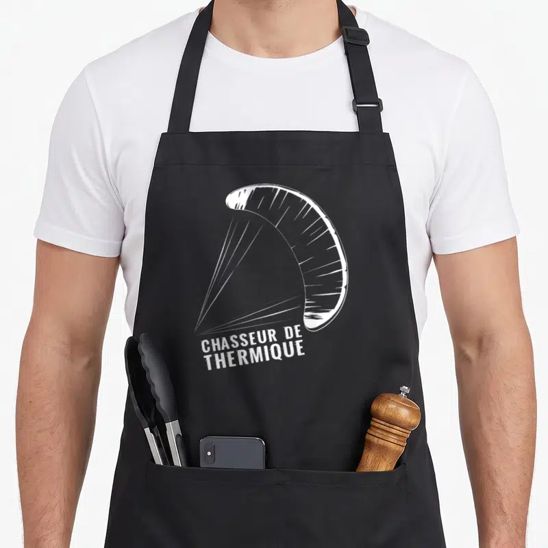 Tablier de cuisine noir avec illustration blanche de parachute et inscription Chasseur de thermique en bas à gauche.