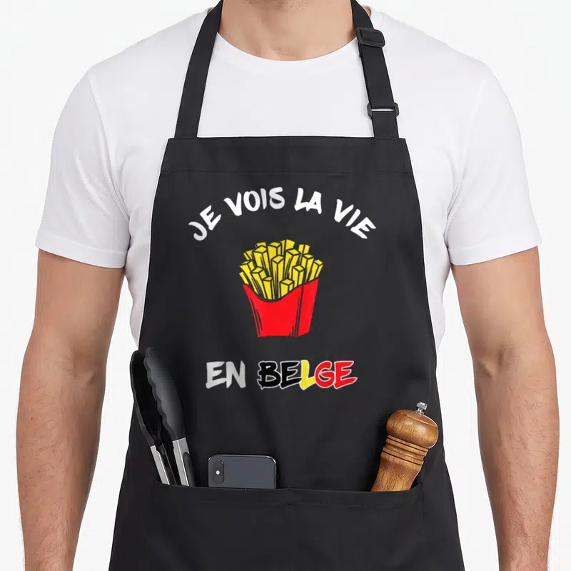 Tablier de cuisine noir avec une pochette de frites jaunes et le texte Je vois la vie en belge en lettres colorées.
