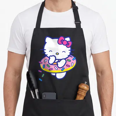 Tablier de cuisine noir avec une illustration de chatte blanche tenant un donut rose aux pépites multicolores