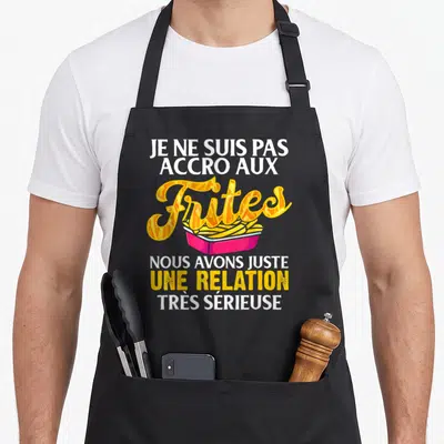 Tablier de cuisine noir avec une boîte de frites roses et le texte Je ne suis pas accro aux frites en blanc et jaune.