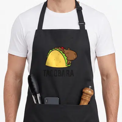Tablier de cuisine noir avec illustration d'une capybara dans un taco et l'inscription TACOBARA.