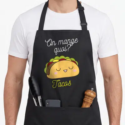 Tablier de cuisine noir avec un taco souriant, la question On mange quoi et l'inscription Tacos en jaune.