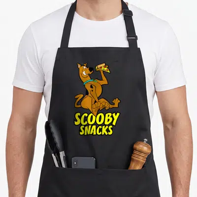 Tablier de cuisine noir avec un chien tenant une pizza et le texte Scooby Snacks en jaune.