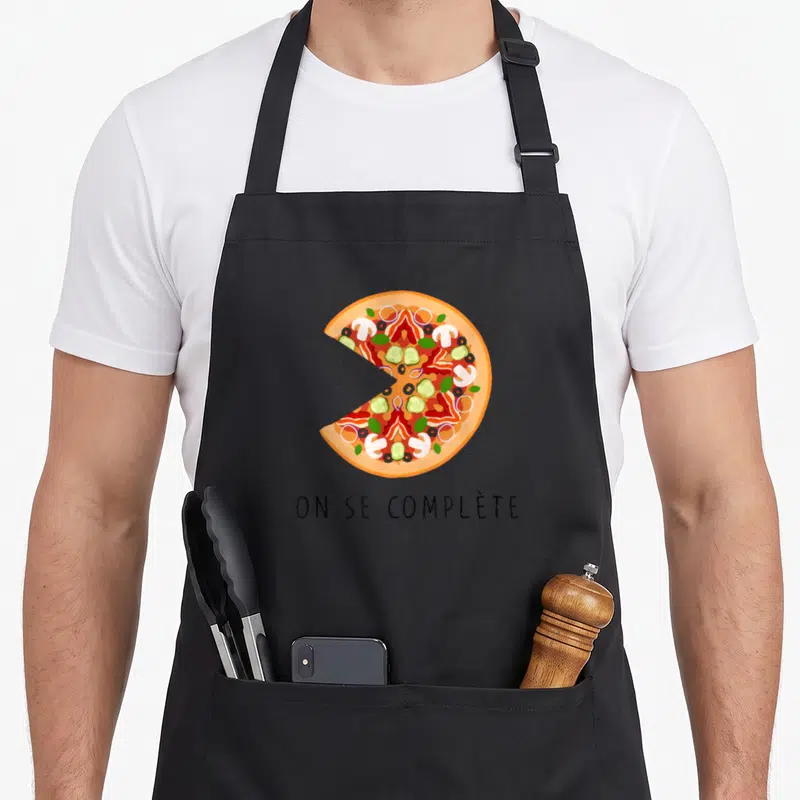 Tablier de cuisine noir avec une illustration colorée d'une part de pizza et un texte en bas.
